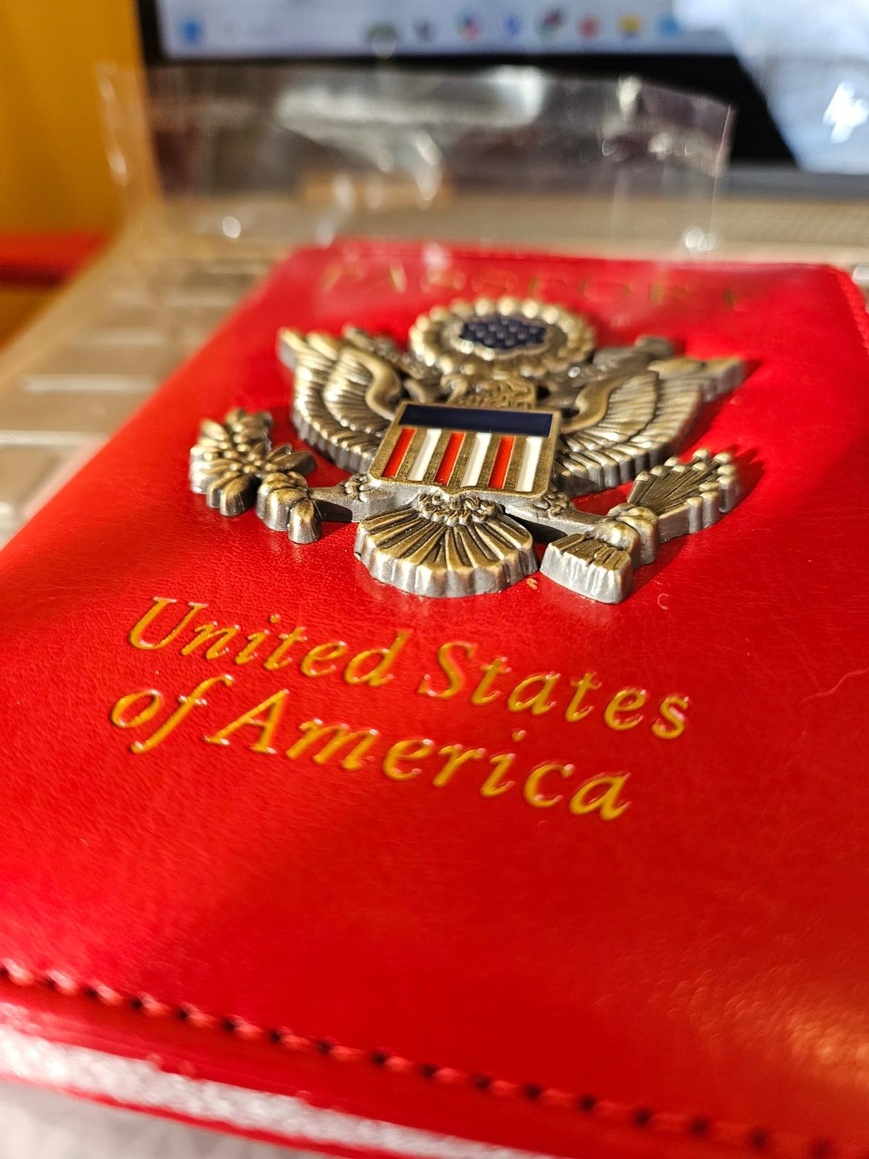 Red case with a gold emblem featuring the United States coat of arms on a wooden surface.
